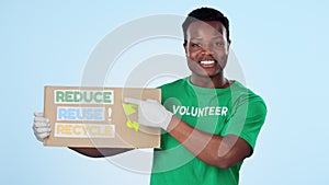 Reduce, reuse and recycle with a black man volunteer pointing to a sign on blue background in studio. Portrait, smile