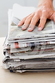 Reduce, reuse, recycle. a hand on top of a stack of newspapers.