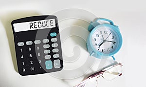 Reduce word written on calculator and white background with clock and glasses