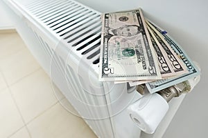 Reduce your energy bill for house heating with us dollars banknotes on white radiator