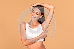 Reducing body odor. Happy fit lady standing with one hand up, demonstrating her smooth depilated armpit