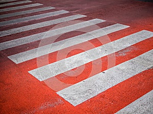 Redâ€‹ Crosswalk on the road, Pedestrian crossing with red and white stripes without people close up. The concept of safety on the