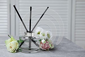 Reed air freshener and flowers on grey table indoors