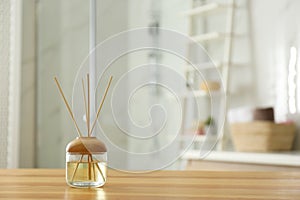 Reed air freshener on table in bathroom. Space for text