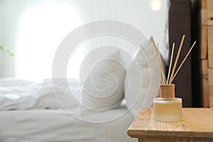 Reed diffuser on nightstand near bed in room