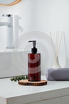 Reed diffusers and a folded towel displayed behind a pump bottle dispenser standing on a wooden podium.