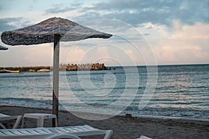 Reed umbrella and sunset over the beach