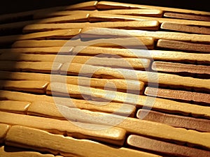 reed or wood mat. The rug is a mat under the hot. Knitted processed wood sticks with rounded edges. Close-up. Yellow  brown and