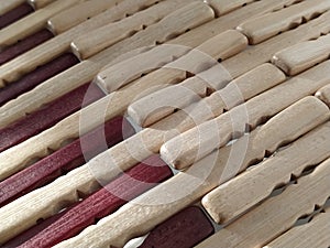 Reed or wood mat. The rug is a mat under the hot. Knitted processed wood sticks with rounded edges. Close-up. Yellow, brown and