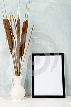 Reeds in a vase and photo frame with a place for text, blank for design. Copy space