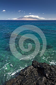 Reef in clear water with view of West Maui Mountains from south shore. Maui, Hawaii, USA