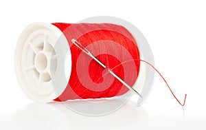 Reel with thread and needle on a white background