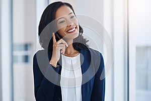 Reeling in new connections for her company. a young businesswoman talking on a cellphone in an office.