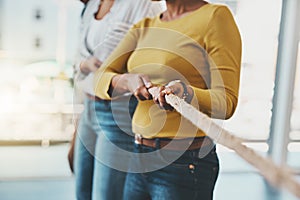 Reeling in success as a team. Closeup shot of two unrecognizable women pulling on a rope.