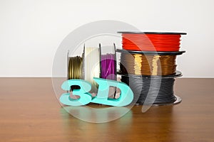3D printing filament reels with text `3d` on wooden background photo