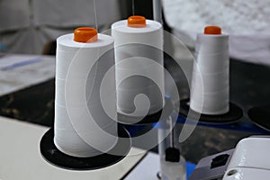 Reels of textile yarn thread at industrial sewing machine