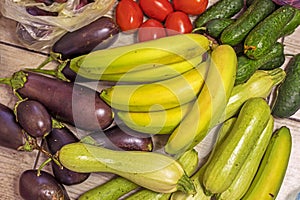 reen bananas lie next to cucumbers, tomatoes and other vegetables. photo