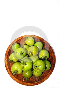 reen tomatoes in a wooden plate, on a white background