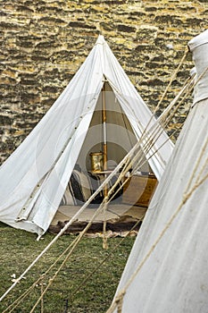 Reenactment of a medieval scene against the historical backdrop of an old city wall, village with tents of various designs with