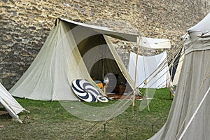 Reenactment of a medieval scene against the historical backdrop of an old city wall, village with tents of various designs with