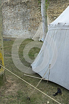 Reenactment of a medieval scene against the historical backdrop of an old city wall, village with tents of various designs with