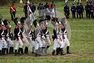 Reenactors dressed as Napoleonic war soldiers march on the battle field