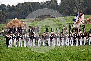 Reenactors dressed as Napoleonic war soldiers march on the battle field