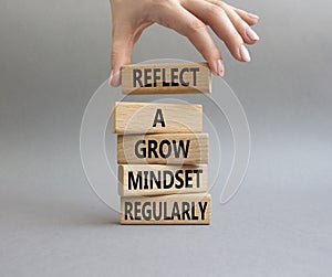 Refclect a grow mindset regularly symbol. Wooden blocks with words Refclect a grow mindset regularly. Businessman hand. Beautiful