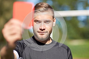 Referee on football field showing red card