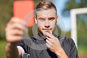 Referee on football field showing red card