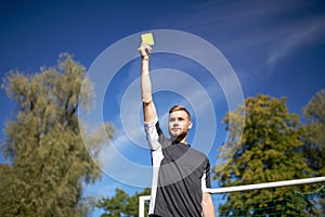 Referee on football field showing yellow card