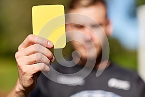 Referee on football field showing yellow card