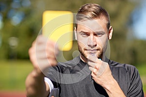 Referee on football field showing yellow card