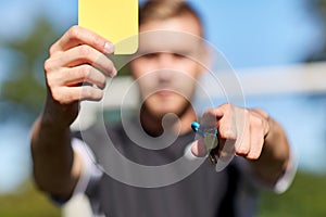 Referee on football field showing yellow card