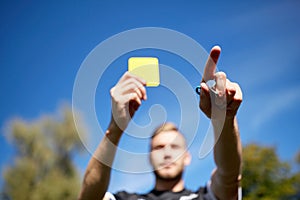 Referee on football field showing yellow card
