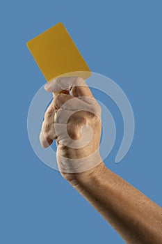 Referee hand holding yellow punishment card