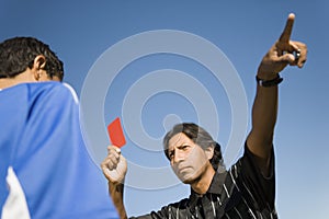 Referee holding up red card and pointing