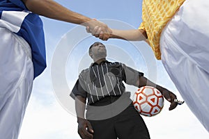 Referee With Opponent Team Players Shaking Hand Against Sky