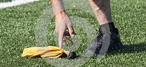 Referee picking up a yellow penalty flag