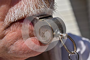 A referee`s old metal whistle is in the mouth of a coach or referee.
