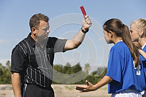 Referee showing red card to girls playing soccer