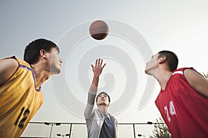 Referee throwing ball in the air, basketball players getting ready for a jump