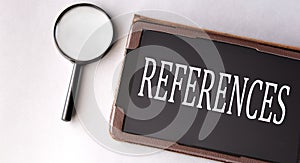 REFERENCES - word in electronic notebook on white background with magnifying glass