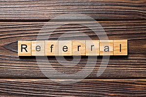 Referral word written on wood block. Referral text on wooden table for your desing, Top view concept