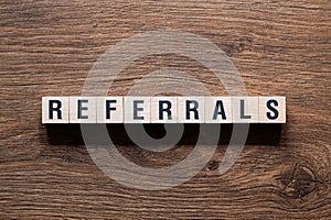 Referrals - word concept on building blocks, text
