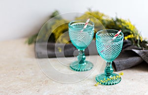 Refhesing drink in blue vintage goblets on the white background with srping flowers