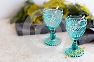 Refhesing drink in blue vintage goblets on the white background with srping flowers