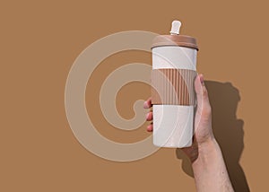 Refillable cup in young mans hand on beige background. Concept of plastic-free and zero waste living