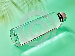 Refillable drinking water bottle on mint green background