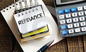 REFINANCE word in a small office notebook next to the calculator